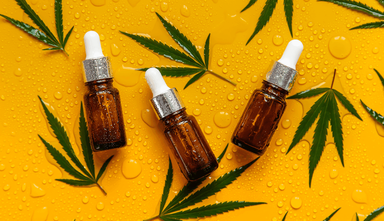 Extrakte und nasse Cannabis Blätter auf gelbem Hintergrund